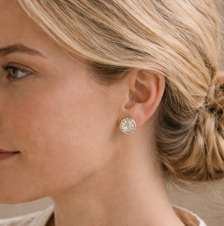 Woman with styled hair and earrings against a neutral background