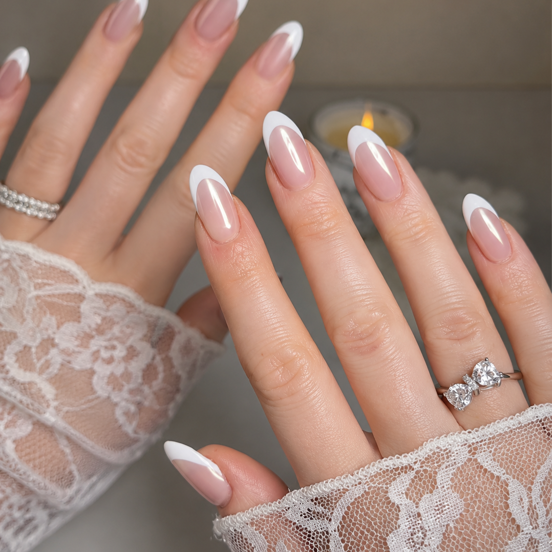 Close-up of hands with lace gloves and white nail polish, wearing a ring.
