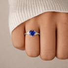 Heart-shaped blue gemstone ring on a finger with a neutral background