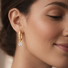 Close-up of a woman wearing gold hoop earrings with a blurred background