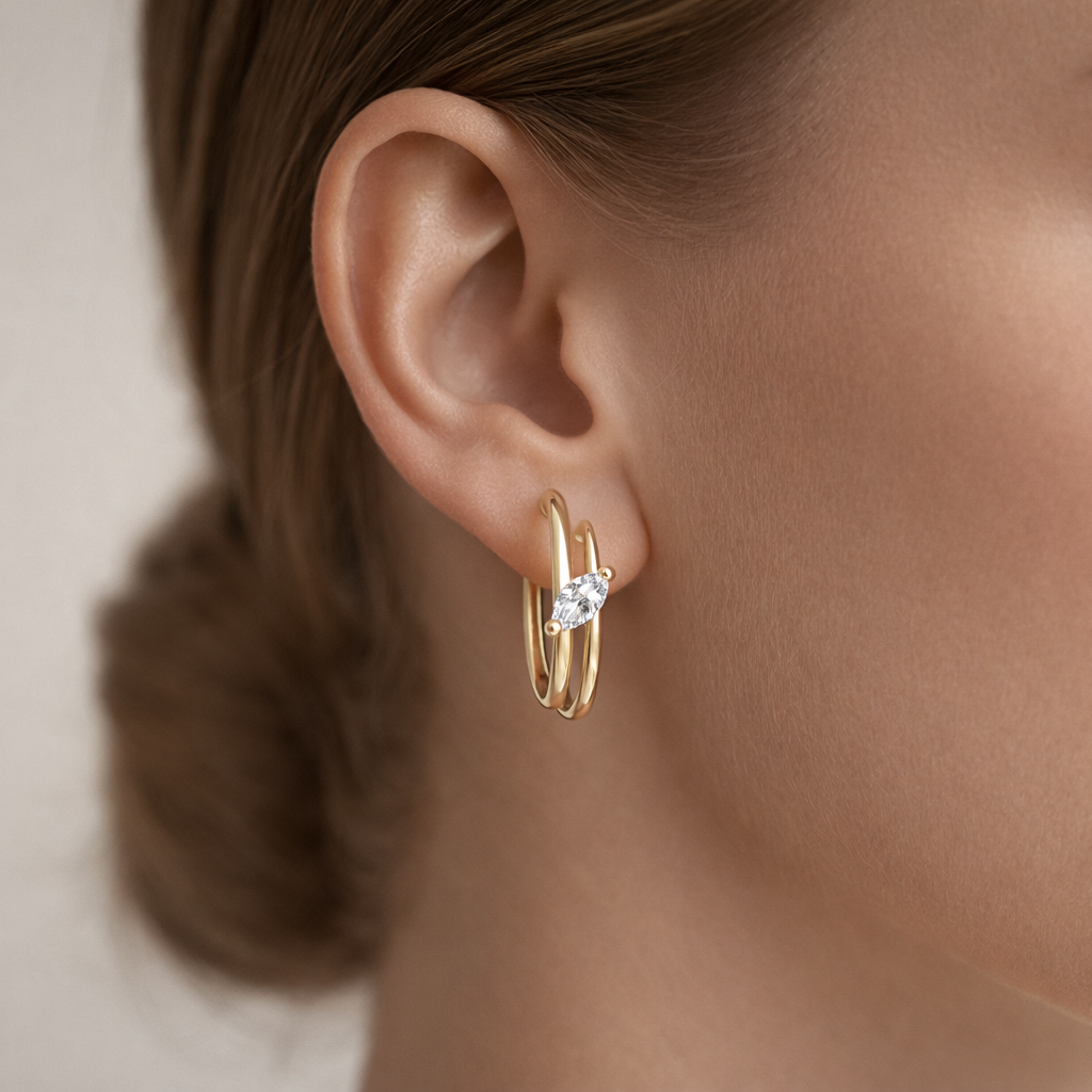 Close-up of a person wearing gold hoop earrings with a diamond.