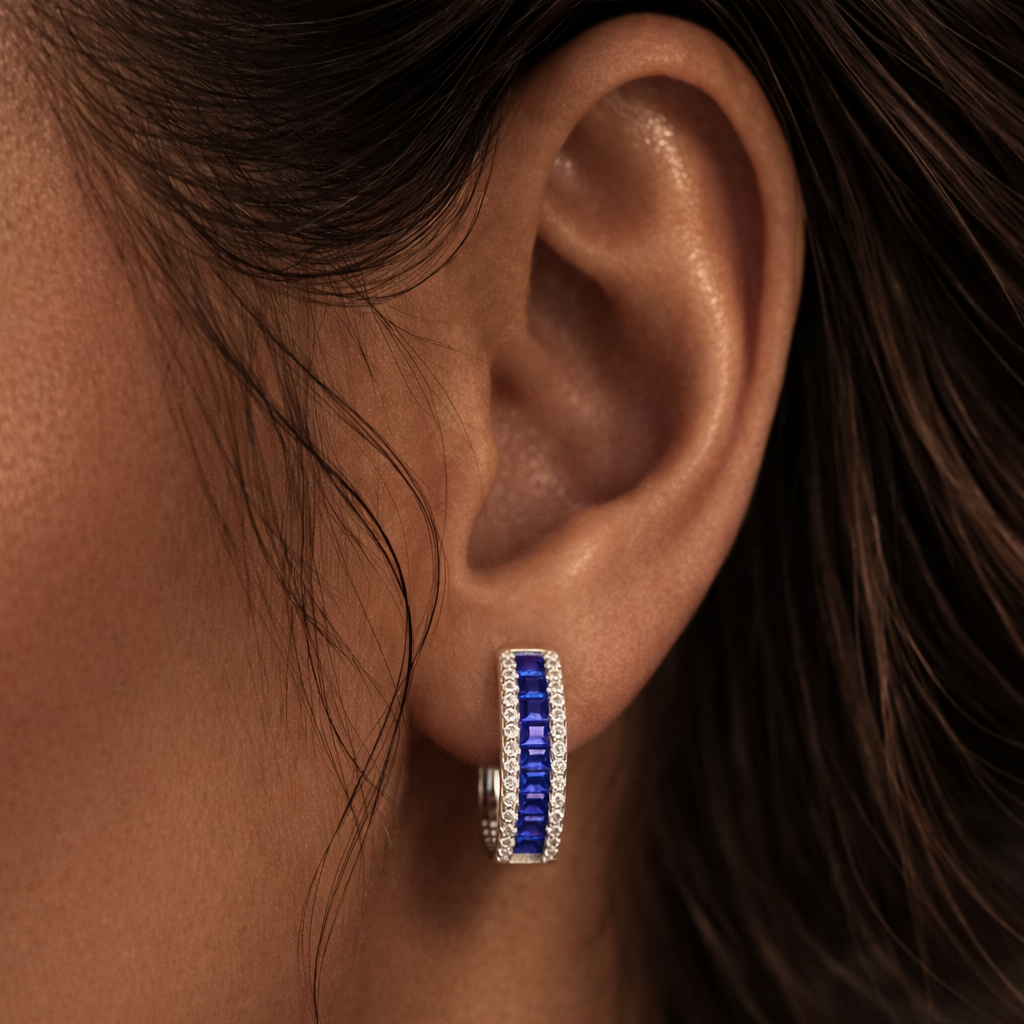 Close-up of an ear wearing a silver earring with blue stones.
