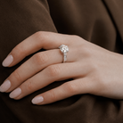 Close-up of a hand wearing a diamond ring on a brown fabric background