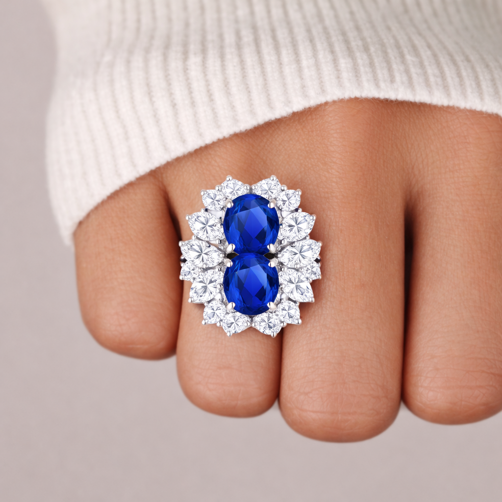 Ring with blue gemstones and diamond-like stones on a finger against a neutral background