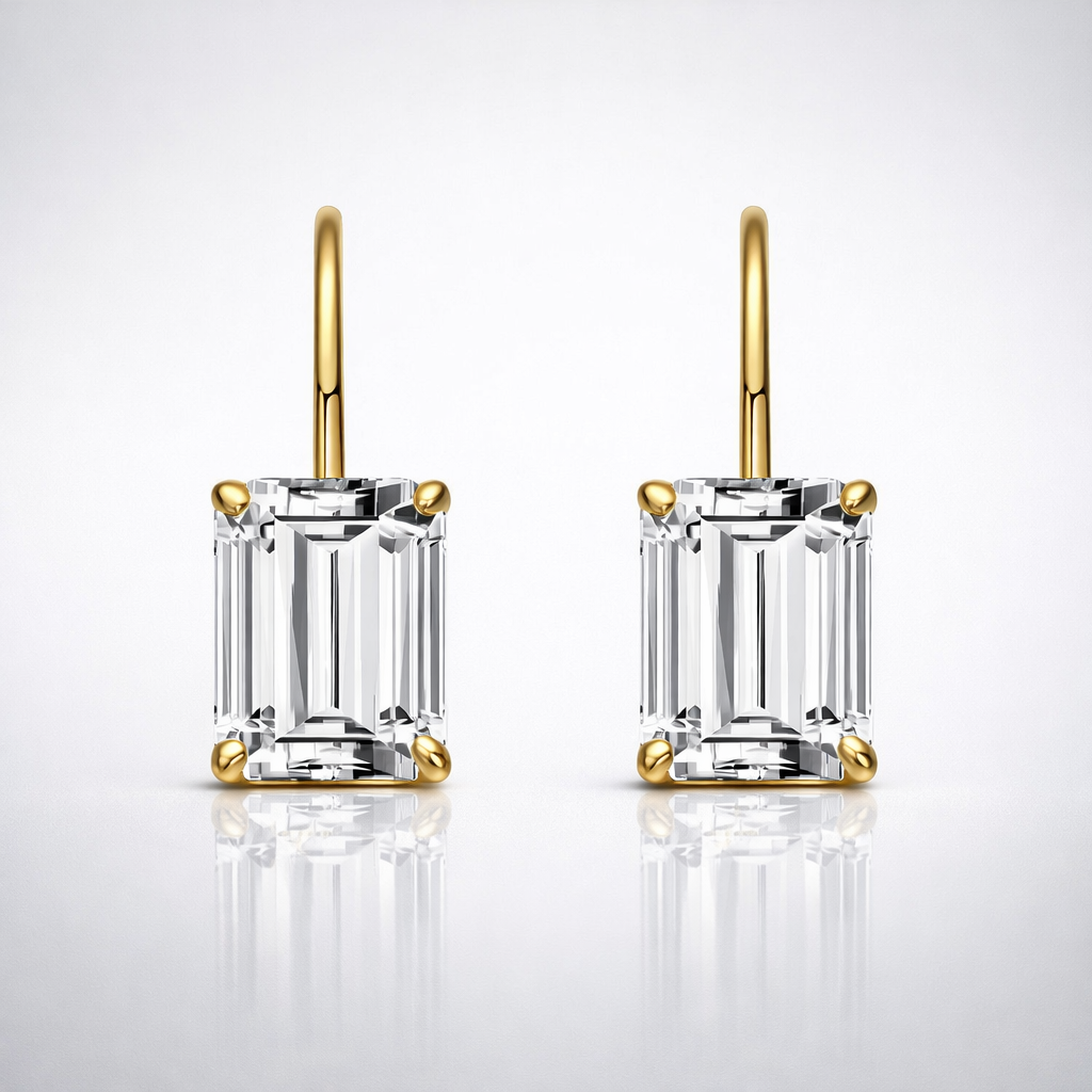 Pair of gold emerald-cut diamond earrings on a light gray background