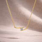 Gold necklace with a small blue gemstone on a beige fabric background