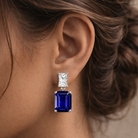 Earring with blue gemstone and clear stone on a blurred background