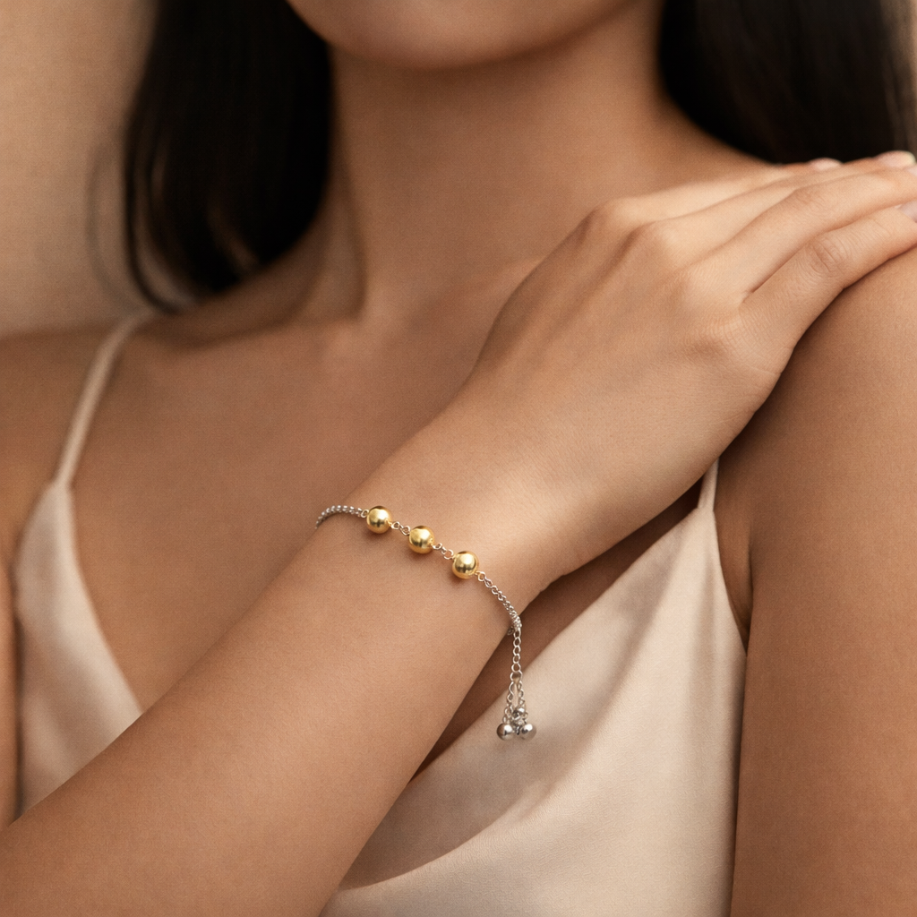 Woman wearing a bracelet with gold beads on a neutral background