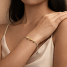Woman wearing a bracelet with gold beads on a neutral background