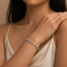 Close-up of a woman's arm wearing a diamond bracelet against a neutral background