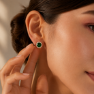 Close-up of a woman wearing green gemstone earrings with a neutral background