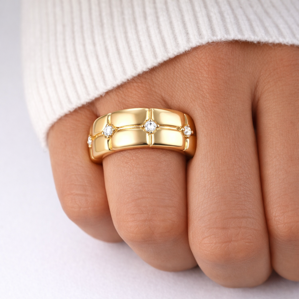 Gold ring with diamonds on a finger against a white background