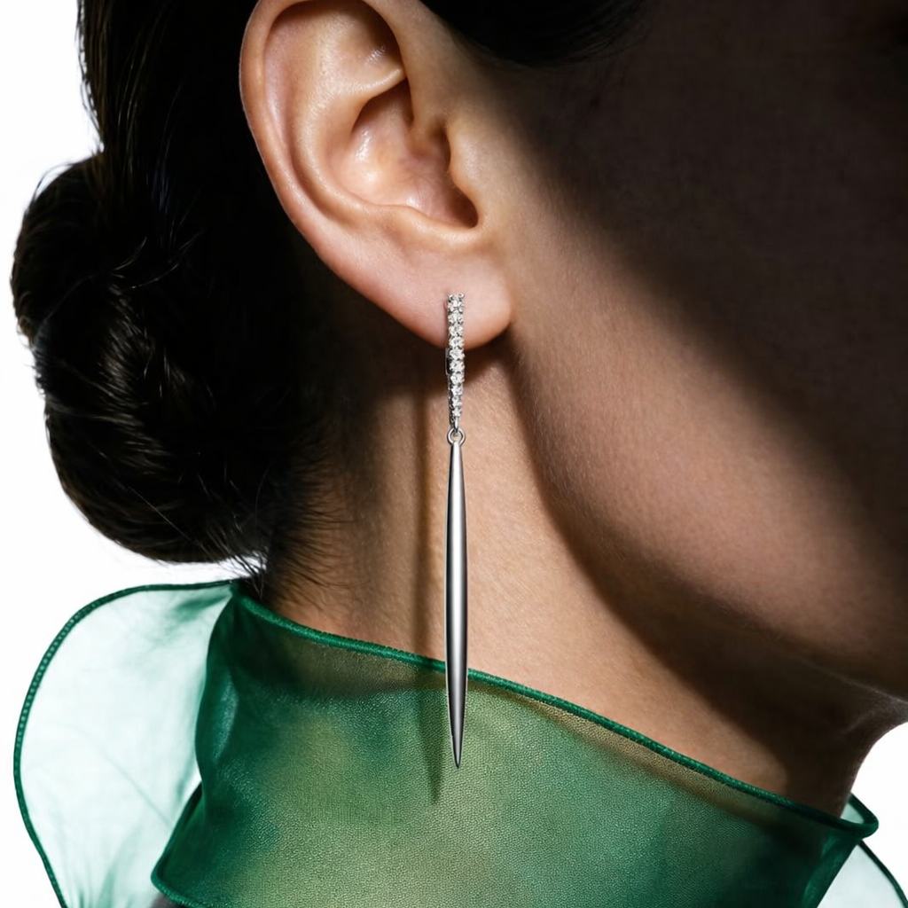 Close-up of an ear wearing a silver earring with a green sheer garment.