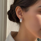 Close-up of a person wearing a pearl earring with a neutral background