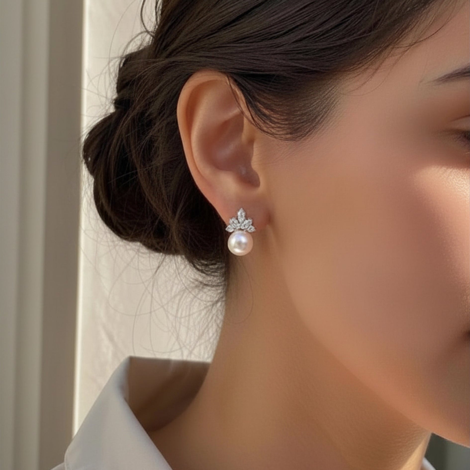 Close-up of a person wearing a pearl earring with a neutral background