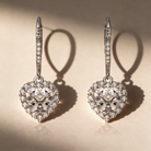 Heart-shaped diamond earrings on a beige background