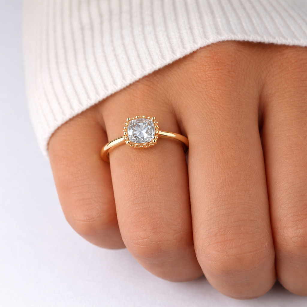Gold ring with a diamond on a person's finger against a white background
